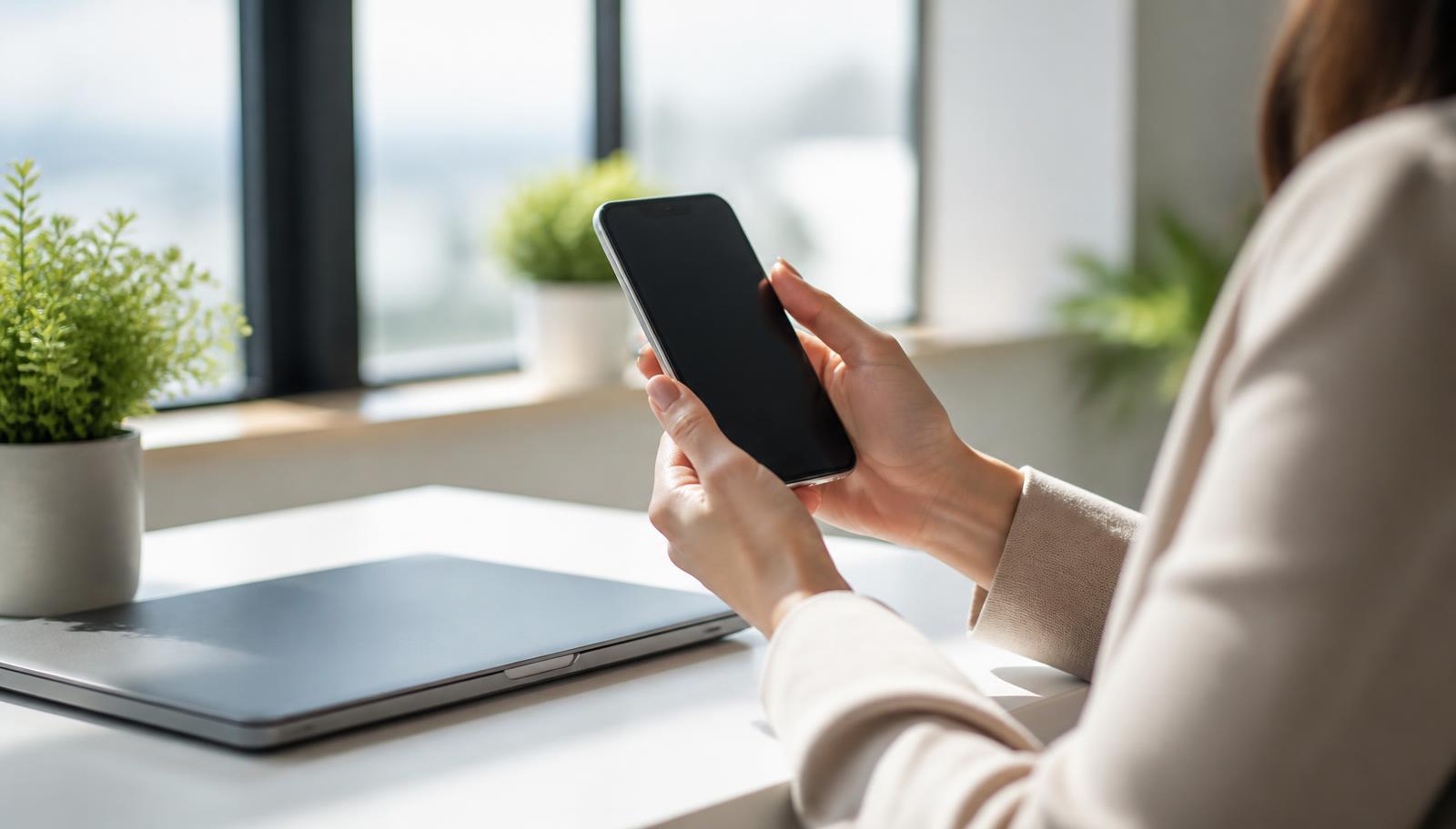Marketer reviewing an Instagram feed on a phone beside a laptop showing social media ad performance charts